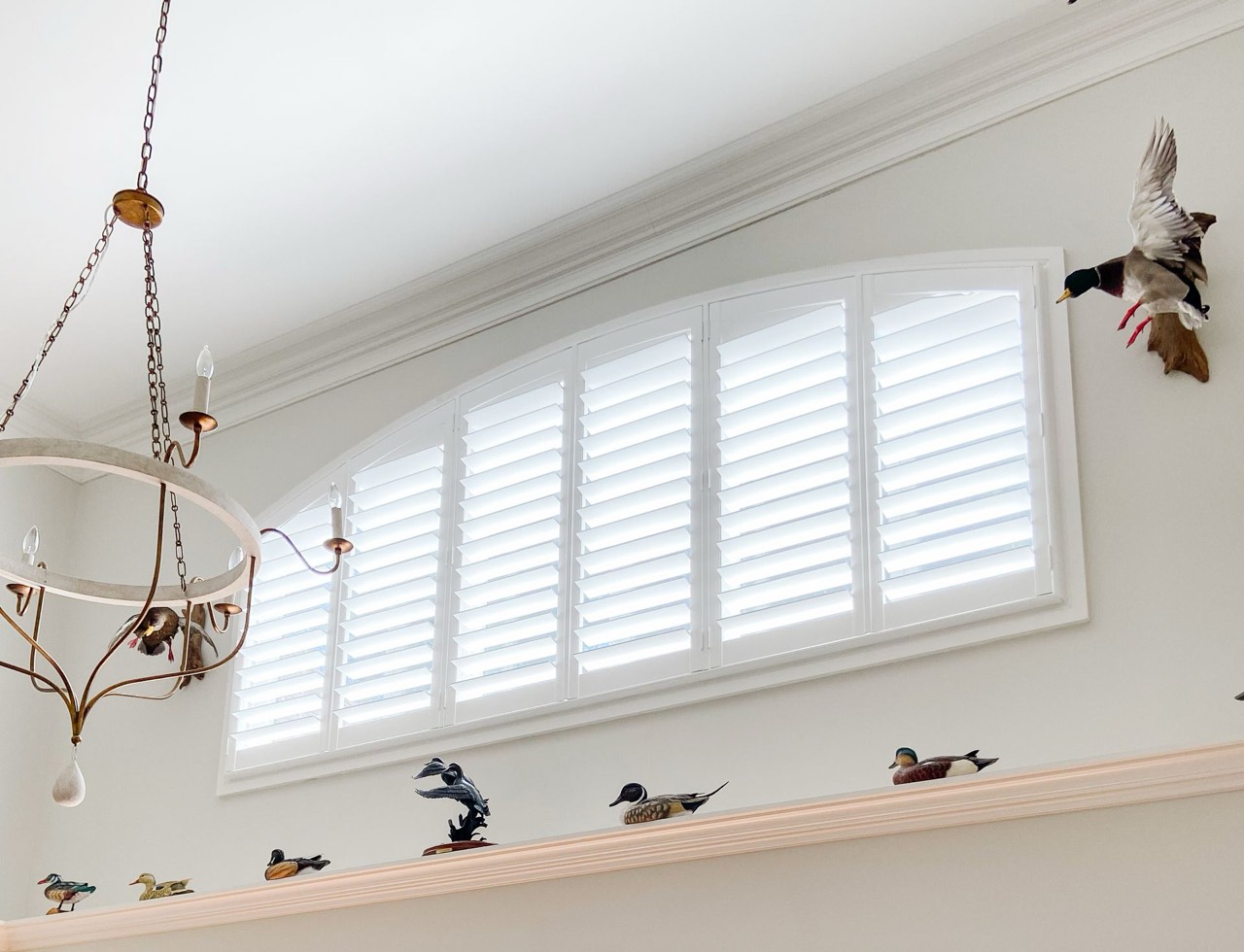 Six-panel arch-top plantation shutters across a wide opening