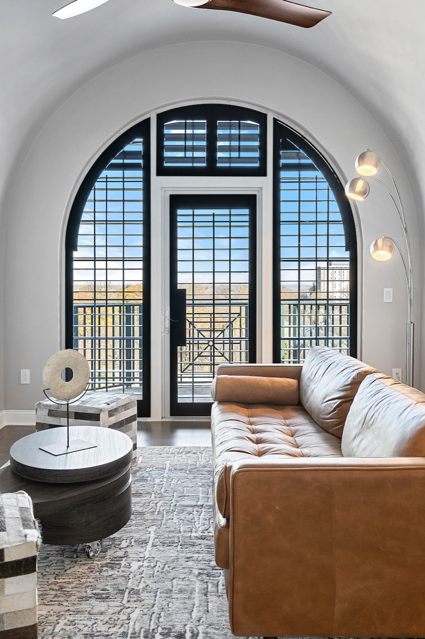 Custom black arch-top plantation shutters framing an interior doorway in a coastal home.