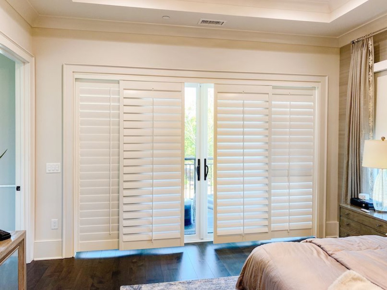 Four-panel bypass track shutters across a sliding glass door wall