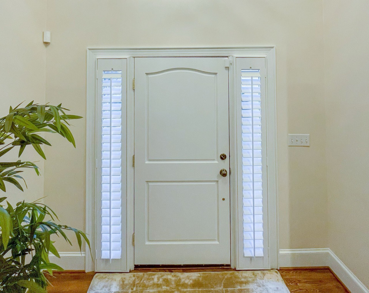Narrow sidelite windows beside a front door fitted with plantation shutters